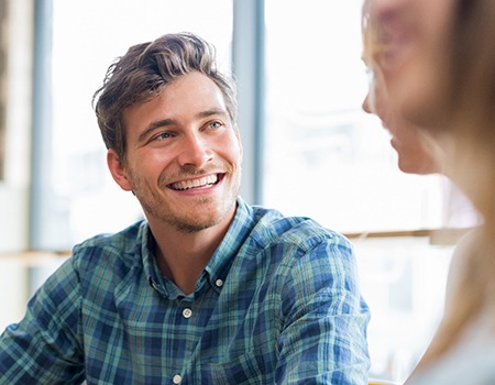 man smiling while talking to friend 