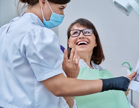Woman smiling with dentist while reviewing X-ray