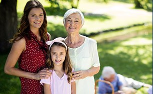 Three generations of family smiling at a picnic outdoors