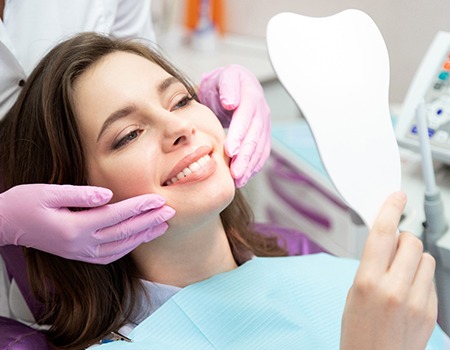 patient smiling while looking in dental mirror 