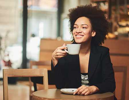 woman smiling while drinking coffee