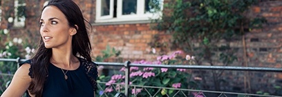 Woman outdoors next to flower garden by brick wall