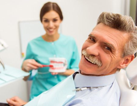 An older man about to receive dentures from his dentist