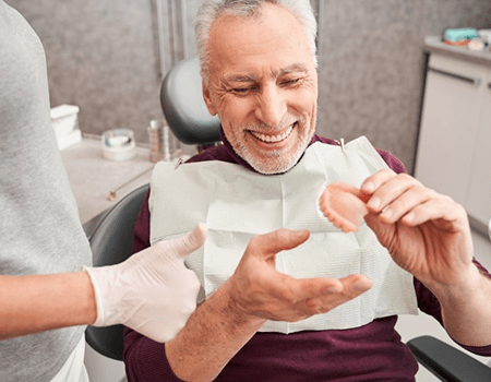 a patient smiling after receiving his new dentures