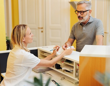 An older man paying the cost of dentures