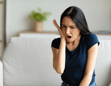 a woman holding her cheek due to a dental emergency