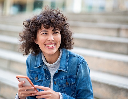 a woman sitting on stairs with her phone out