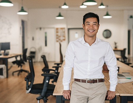 a man leaning against a desk and smiling
