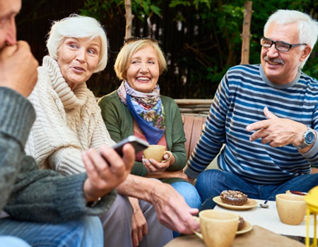 Group of friends laughing while enjoying breakfast outside 