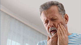 Older man in pain holding jaw