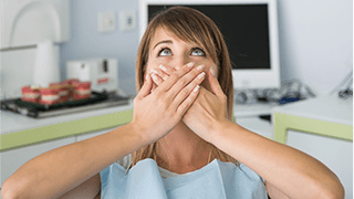 Woman in dental chair covering mouth