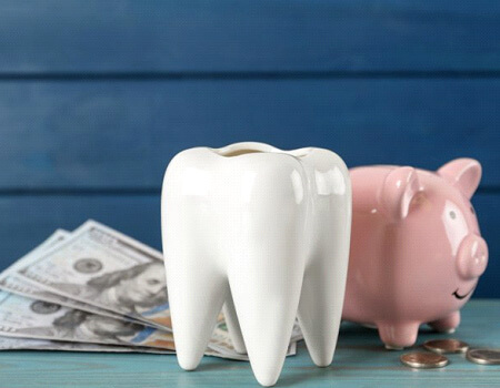 a tooth next to a piggy bank and money