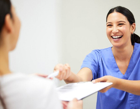 a dental member handing over a form for cost of veneers