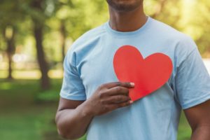 person holding a cutout paper heart up to their chest