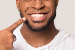 close-up of a man pointing to his smile 