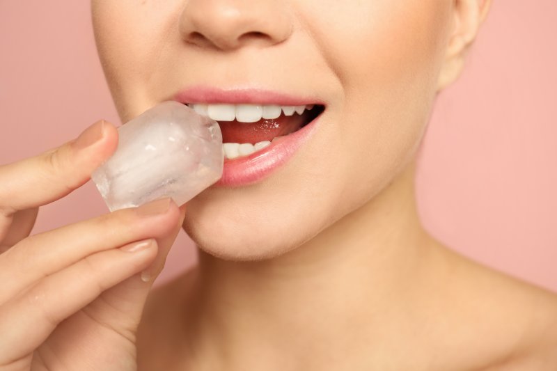 Woman holding up a piece of ice to her mouth