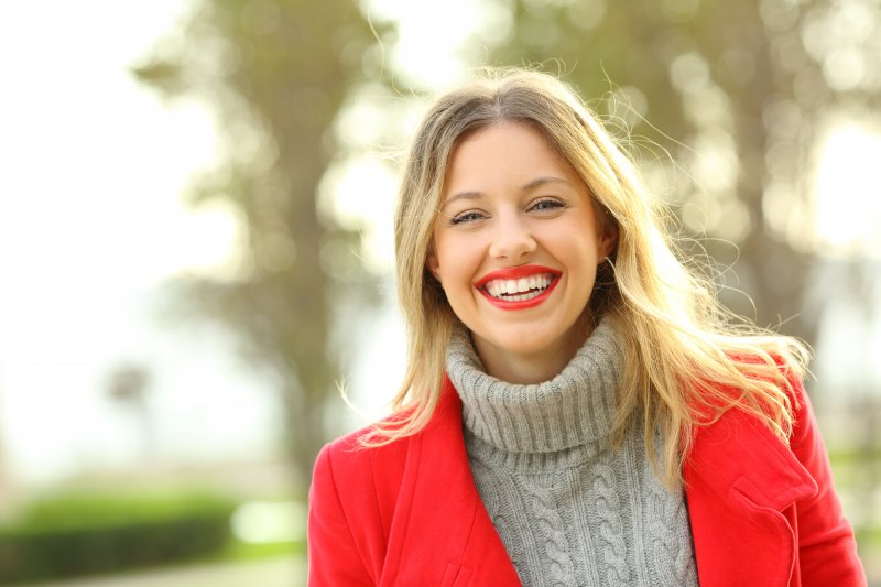 a woman smiling after learning the truth behind cosmetic dentistry myths