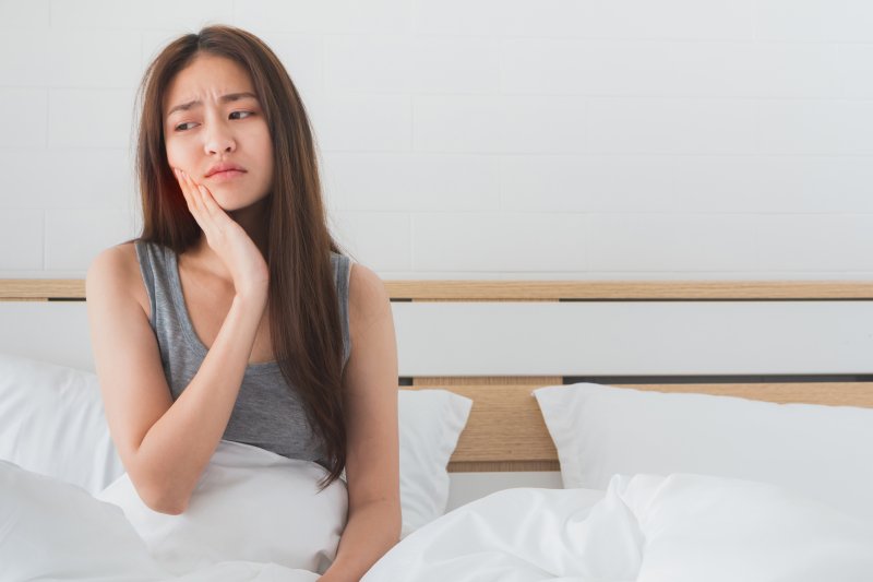 young woman in bed with toothache at night