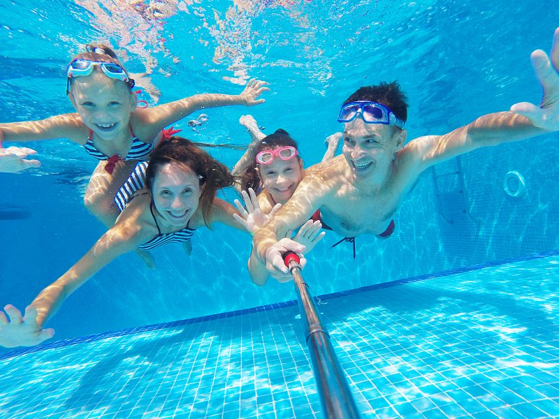 family swimming in a pool during summer