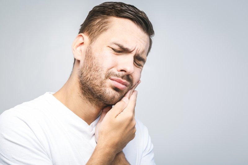 person with dental emergency holding cheek