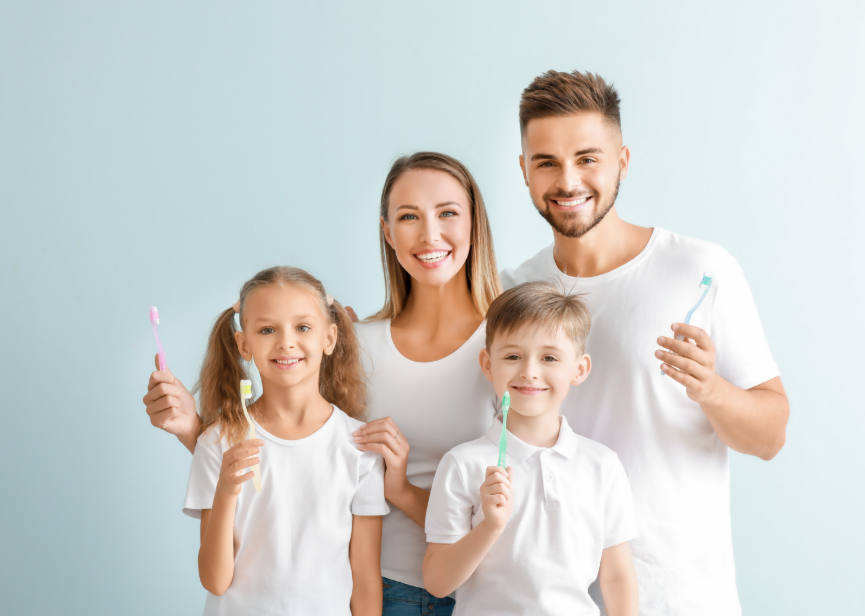 Family holding toothbrushes and smiling