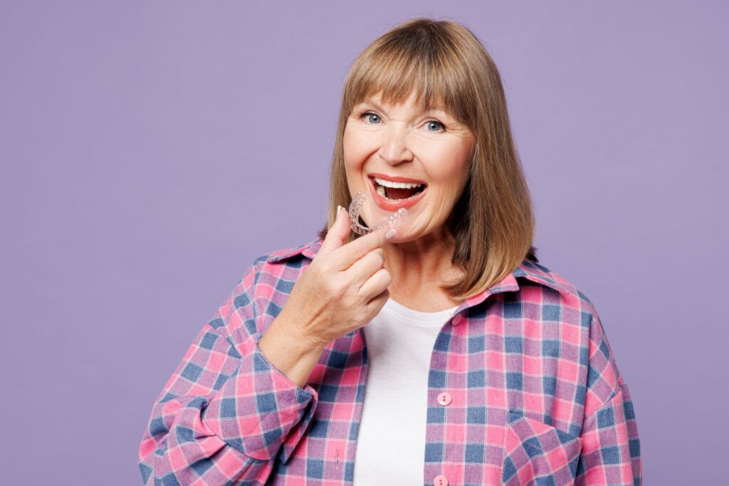 An older woman putting on an Invisalign aligner